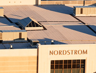 Aerial view of a Nordstrom retail building with a sunlit roof and prominent signage.